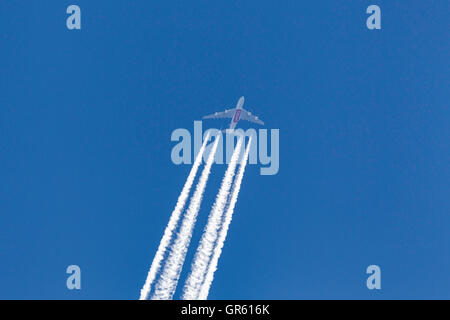 Emirates Airlines Airbus A380 super jumbo aircraft at high altitude with long white contrail streaming behind the aircraft. Stock Photo