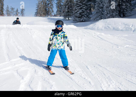 Cute little boy, skiing happily in Austrian ski resort in the mountains, wintertime Stock Photo