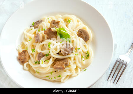 Spaghetti pasta with grilled mushrooms and greens on white plate Stock Photo