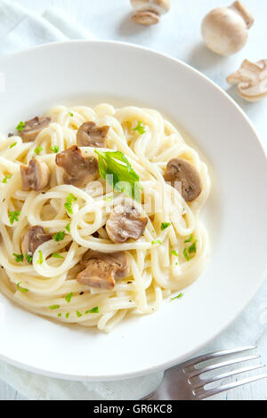 Spaghetti pasta with grilled mushrooms and greens on white plate close up Stock Photo