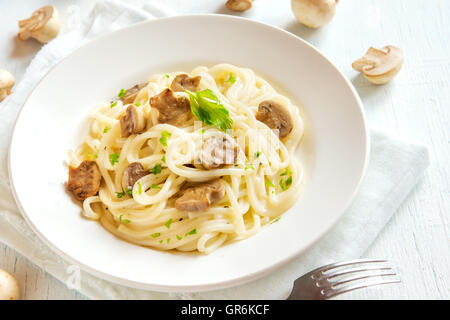 Spaghetti pasta with grilled mushrooms and greens on white plate Stock Photo