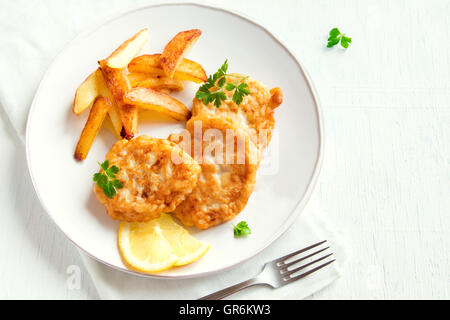 Homemade fish cakes with french fries over white wooden background with copy space Stock Photo