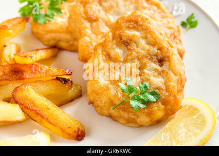 Homemade fish cakes with french fries on white plate close up Stock Photo