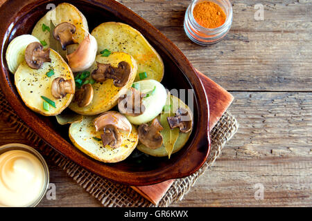 Oven baked potatoes with mushrooms and spices in rustic baking dish Stock Photo