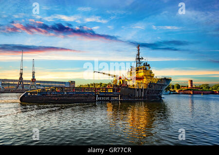 Tug boat at sunrise coming to port. Stock Photo
