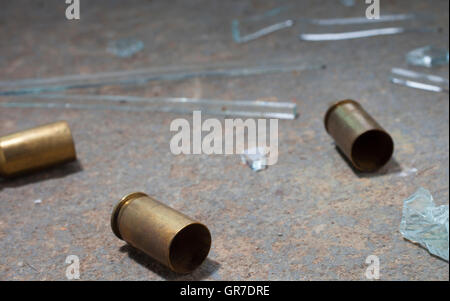 Handgun shells that have been shot on concrete with glass around Stock Photo