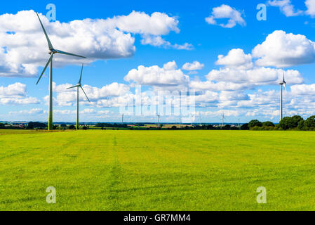 Sustainable energy from wind turbines in flat farmland with fine clouds overhead. Skane in southern Sweden. Stock Photo