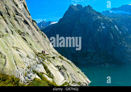 Hiking Trail To The Mountain Cabin Gelmerhütte Along The Rocky Shore Of The Hydroelectric Water Reservoir Lake Gelmersee, Grimsel, Switzerland Stock Photo