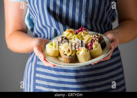 Woman Holding Plate Of Delicious Homemade Cupcakes Stock Photo