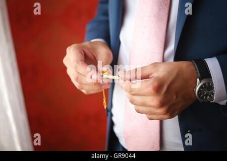 Groom in blue suit putting on tie clip, closeup Stock Photo