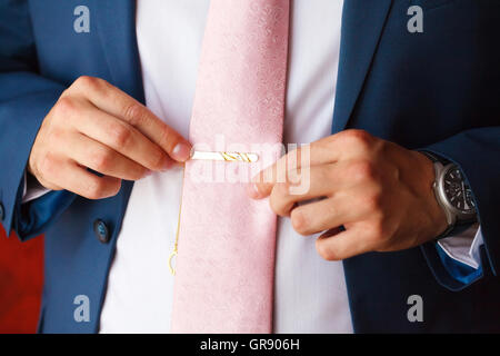 Groom in blue suit putting on tie clip, closeup Stock Photo