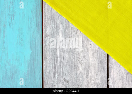 Rustic blue and white painted wooden table with a yellow tablecloth, view from above, copy space. Stock Photo