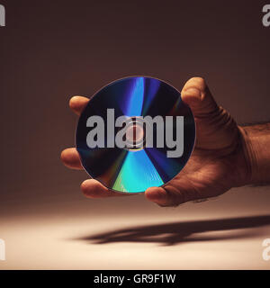 Conceptual composition, CD in a male hand. Stock Photo