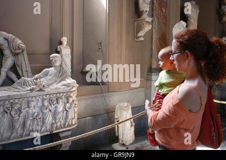 Tourists looking Sarcophagus depicting a child with theatrical mask. Vatican Museum. Stock Photo