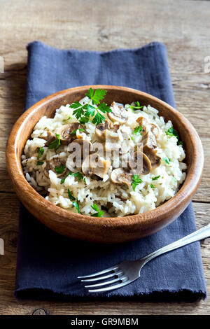 Mushroom risotto with parsley in wooden bowl Stock Photo