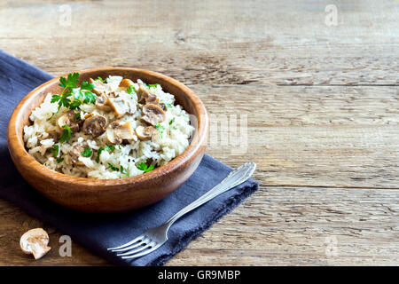 Mushroom risotto with parsley in wooden bowl over rustic background with copy space Stock Photo