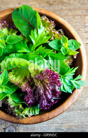 Fresh organic green mixed salad leaves over rustic wooden background Stock Photo
