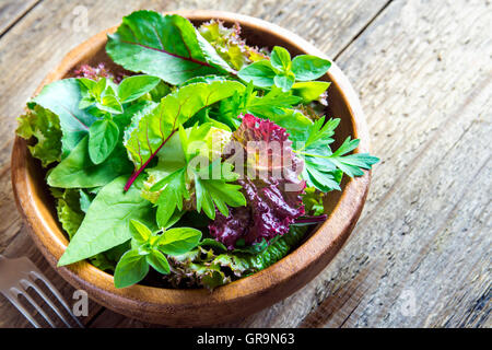 Fresh organic green mixed salad leaves over rustic wooden background with copy space Stock Photo