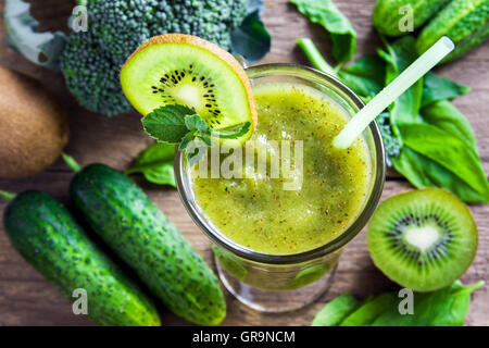 Green vegetable and herbs smoothie with heart of poppy and sesame seeds over rustic wooden background with copy space Stock Photo
