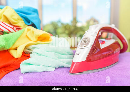 Iron and pile of clothes for ironing. Stock Photo