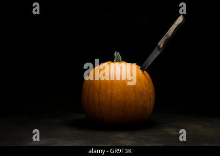 Halloween. pumpkin with knife on a dark background. Studio shot Stock Photo