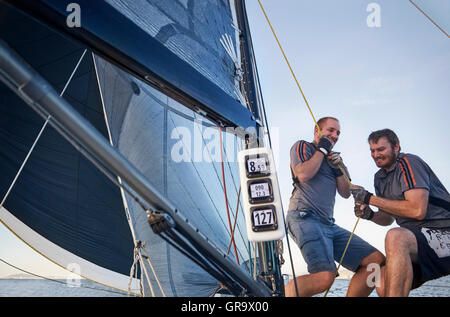 Men sailing pulling rigging equipment on sailboat Stock Photo
