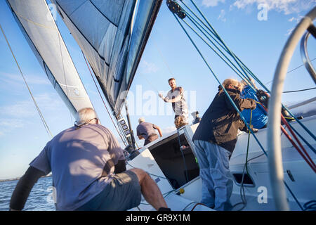 Men sailing adjusting rigging and sail on sailboat Stock Photo