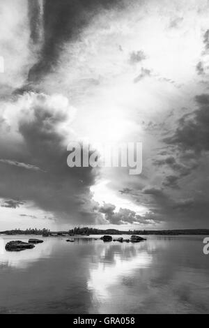 Black And White Photo Of The Reflections Of Dramatic Clouds In The Northern Finnish Lake Inari In Lapland Stock Photo
