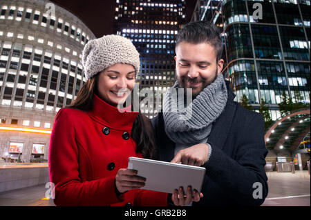 Couple with tablet in winter clothes in night city Stock Photo