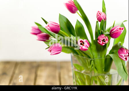 Purple Tulips In A Vase On Old Wooden Table Stock Photo