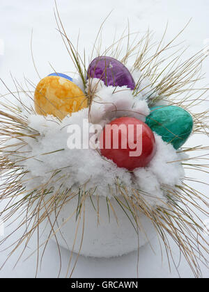 Coloured Easter Eggs Lying In Snow, Symbol Of Easter In Snow Stock Photo