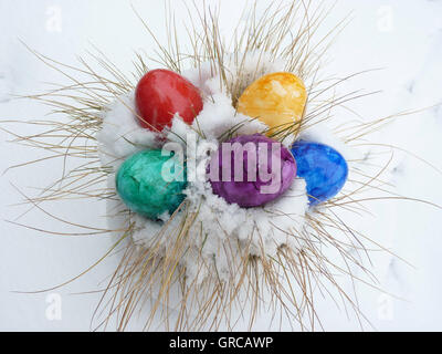 Coloured Easter Eggs Lying In Snow, Symbol Of Easter In Snow Stock Photo