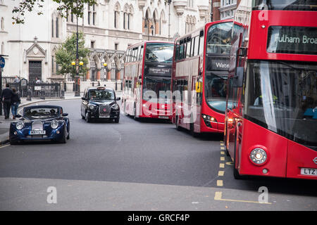 London Red Double Decker Buses, Black Cab Taxis and Morgan Sports Car. Traffic in Central London by the Strand. Stock Photo