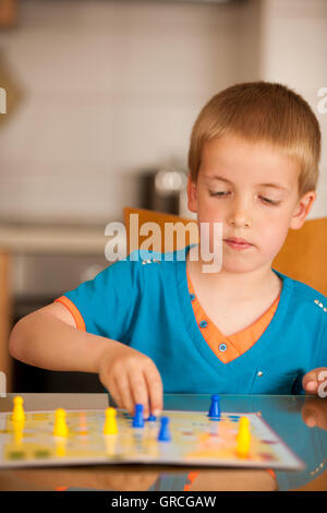 Boy playing ludo game at home. Stock Photo