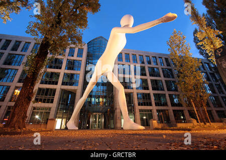 Sculpure Walking Man In Front Of Insurance Company Munich Re At Dusk Stock Photo