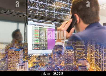 Stock trader looking at computer screens. Stock Photo
