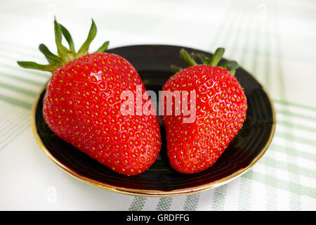Two Strawberries On A Black Plate Stock Photo