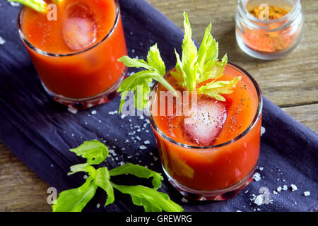 Tomato juice with celery, spices, salt and ice in portion glasses Stock Photo