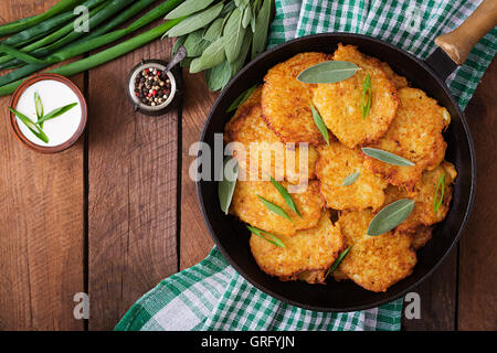 Fried potato pancakes in a frying pan on a wooden table. Top view Stock Photo