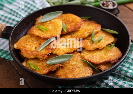 Fried potato pancakes in a frying pan on a wooden table Stock Photo