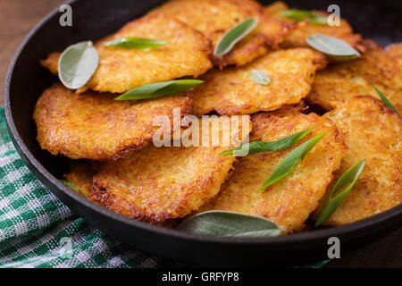 Fried potato pancakes in a frying pan on a wooden table Stock Photo