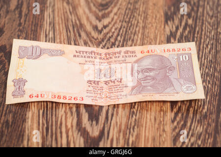 Ten rupee note (Indian Currency) on wooden background Stock Photo