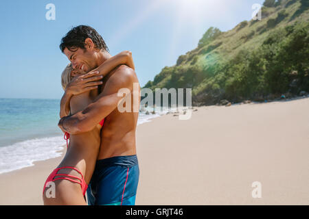 Shot of affectionate young couple on the beach. Man and woman in swimsuits embracing outdoors on a summer day. Enjoying honeymoo Stock Photo