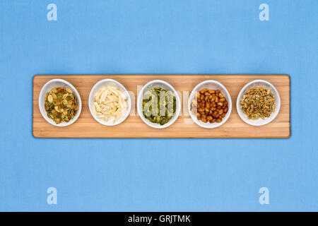 Different types of nuts presented in tater cups on blue background Stock Photo