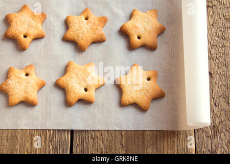 Homemade gingerbread cookies (stars) on baking paper and rustic wooden table Stock Photo