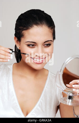young woman putting on mascara Stock Photo