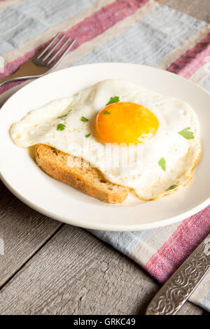 Fried egg on bread for breakfast on plate and rustic table Stock Photo