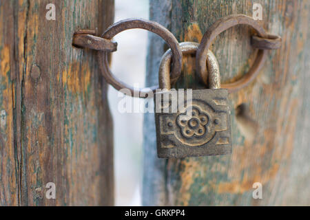 Old Rusty Decorated Padlock on a Wooden Door. Vintage Corroded Padlock on a Ancient Gate Background. Stock Photo