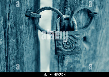 Old Rusty Decorated Padlock on a Wooden Door in Cyan. Vintage Corroded Padlock on a Ancient Gate Background. Stock Photo
