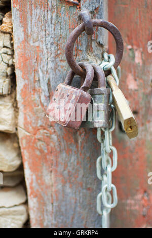 Vintage Corroded Padlocks  with Chain on a Ancient Red Gate Background. Old Rusty Padlocks on a Wooden Door. Stock Photo